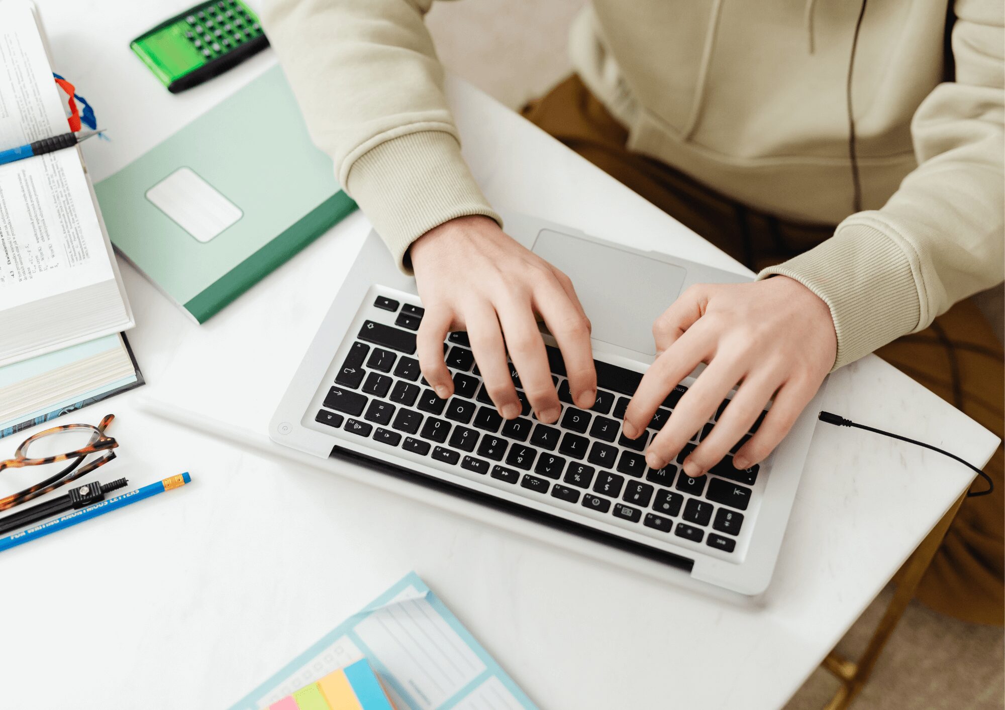 Personne tapant sur le clavier d’un ordinateur portable entouré de livres et de fournitures, illustrant la création d’un site web mémorable pour le blog de Lili Créa Design à Saint-Nazaire.